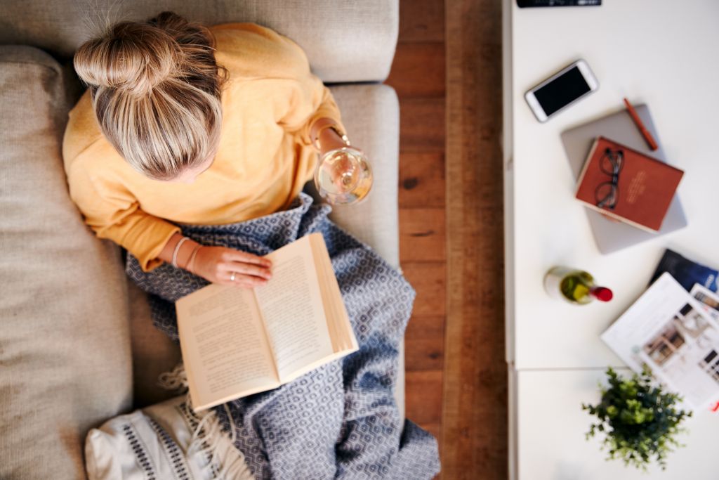 Woman At Home Lying On Reading Book And Drinking Wine